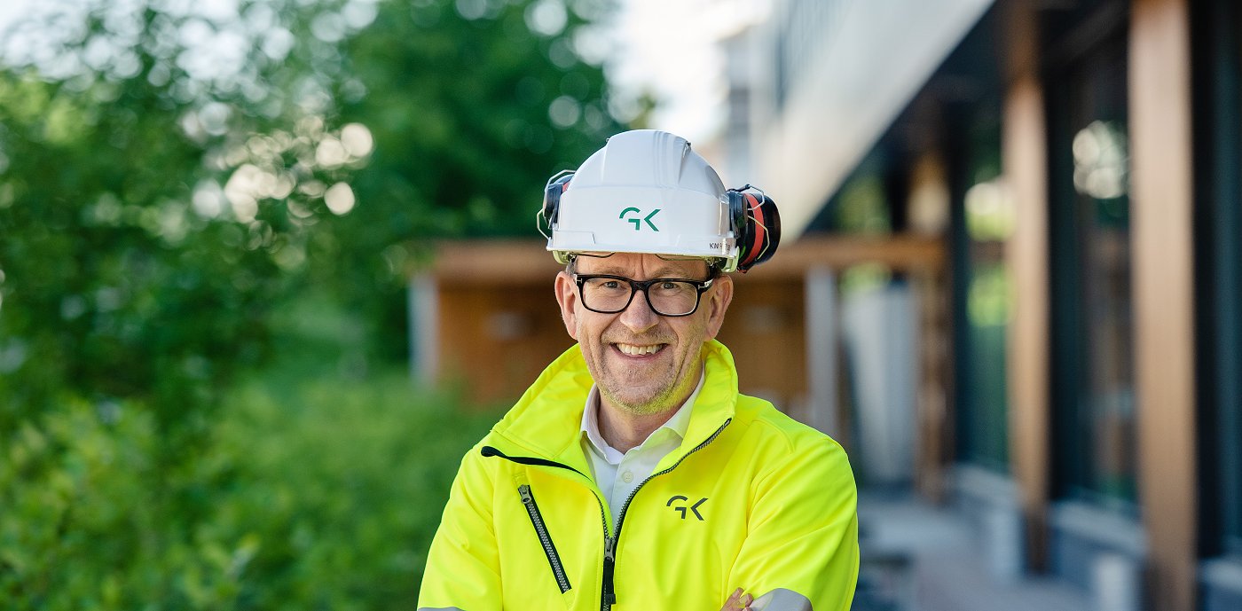 Bilde av Kim Robert Lisø, konsernsjef i GK, utenfor Miljøhuset Ryen i arbeidstøy og hjelm. Bilde av Kim Robert Lisø, konsernsjef i GK, utenfor Miljøhuset Ryen i arbeidstøy og hjelm.